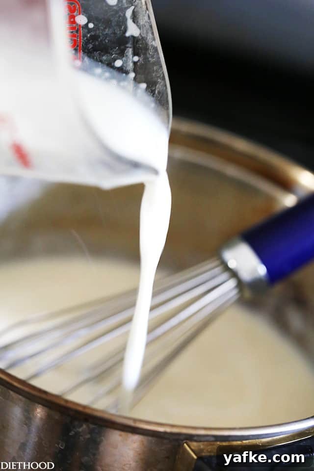 How to Make Classic Béchamel Sauce 2 Milk being added to a roux of flour and butter in a saucepan, with a whisk.