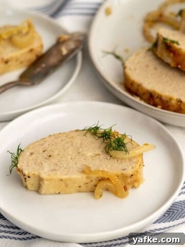 gefilte fish slice on a plate garnished with dill and onion