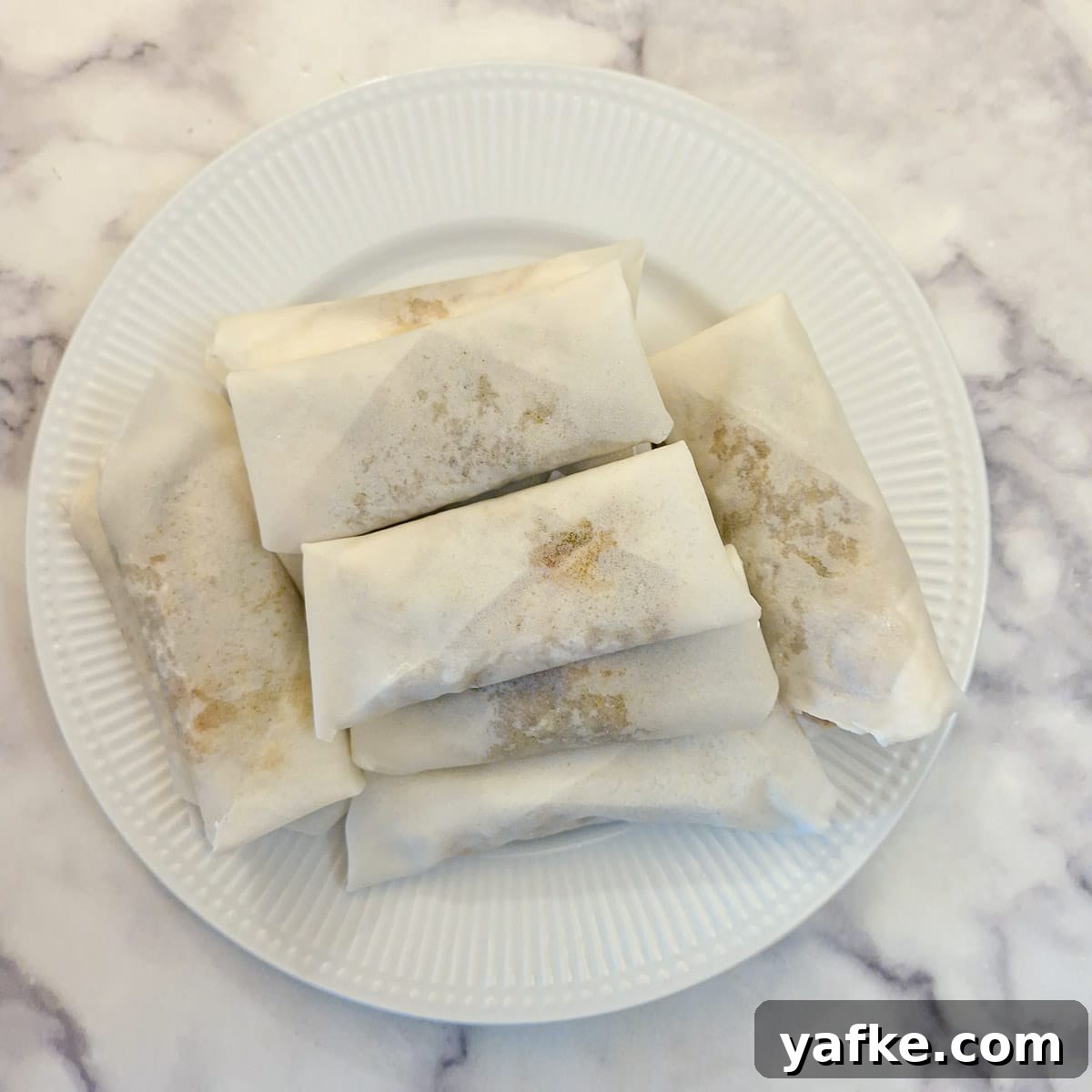 Crispy Prawn Spring Rolls Recipe with Sweet Chili Dip 11 A pile of formed (unfried) spring rolls on a plate.