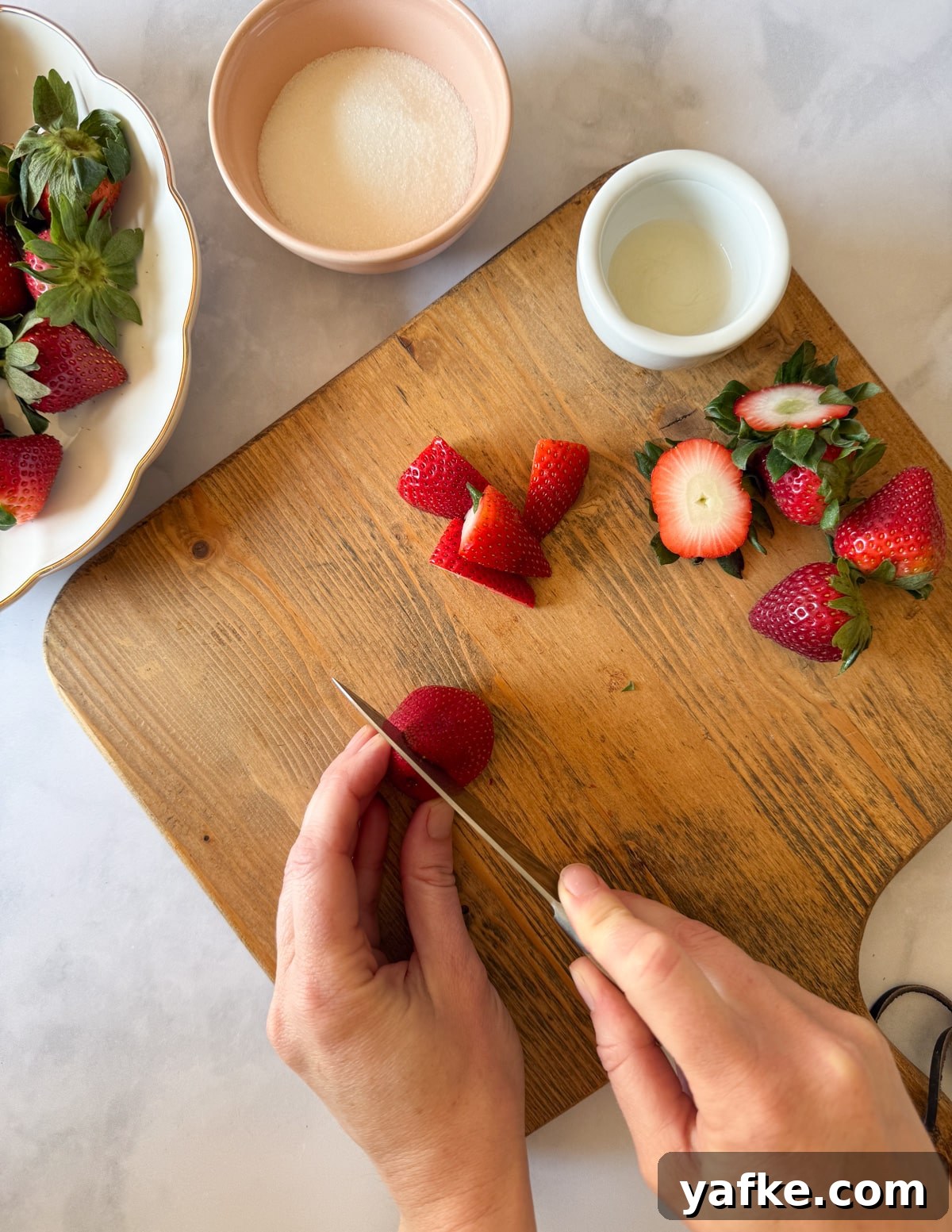 Macerated Strawberries Recipe with Lemon and Vanilla 5 cutting a strawberry in half lengthwise