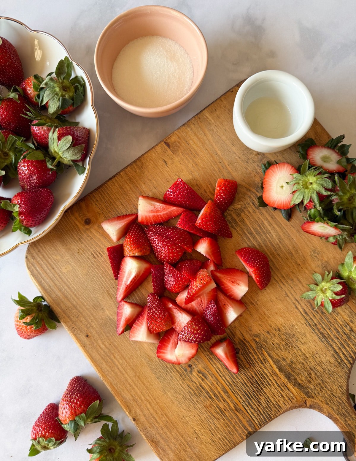 Macerated Strawberries Recipe with Lemon and Vanilla 7 quartered strawberries on a cutting board.