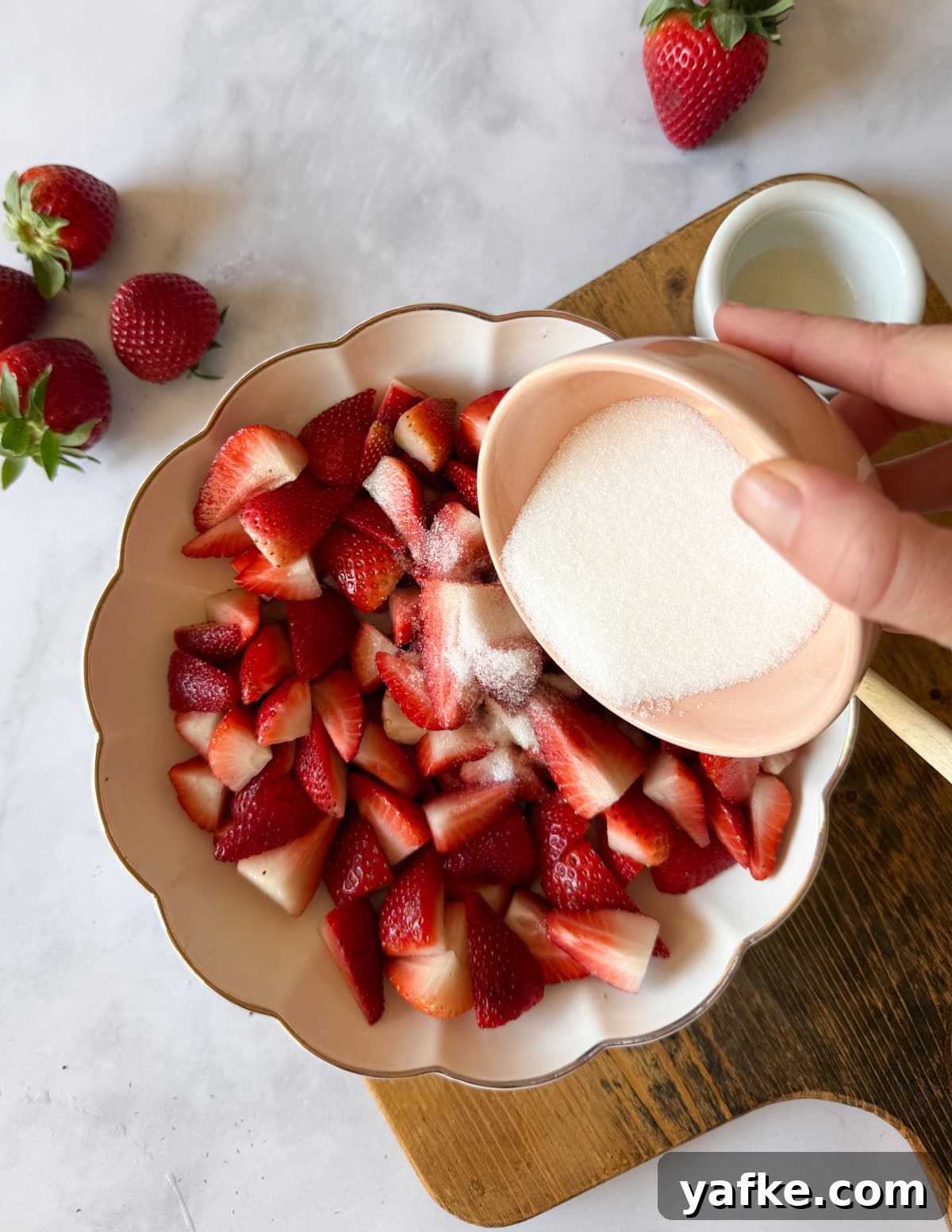 Macerated Strawberries Recipe with Lemon and Vanilla 8 pouring a bowl of sugar on some strawberries