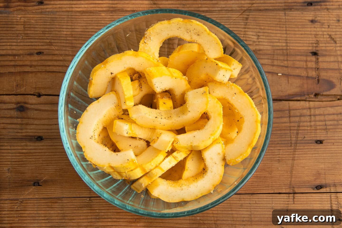 Picture of cut delicata squash in a bowl with spices.