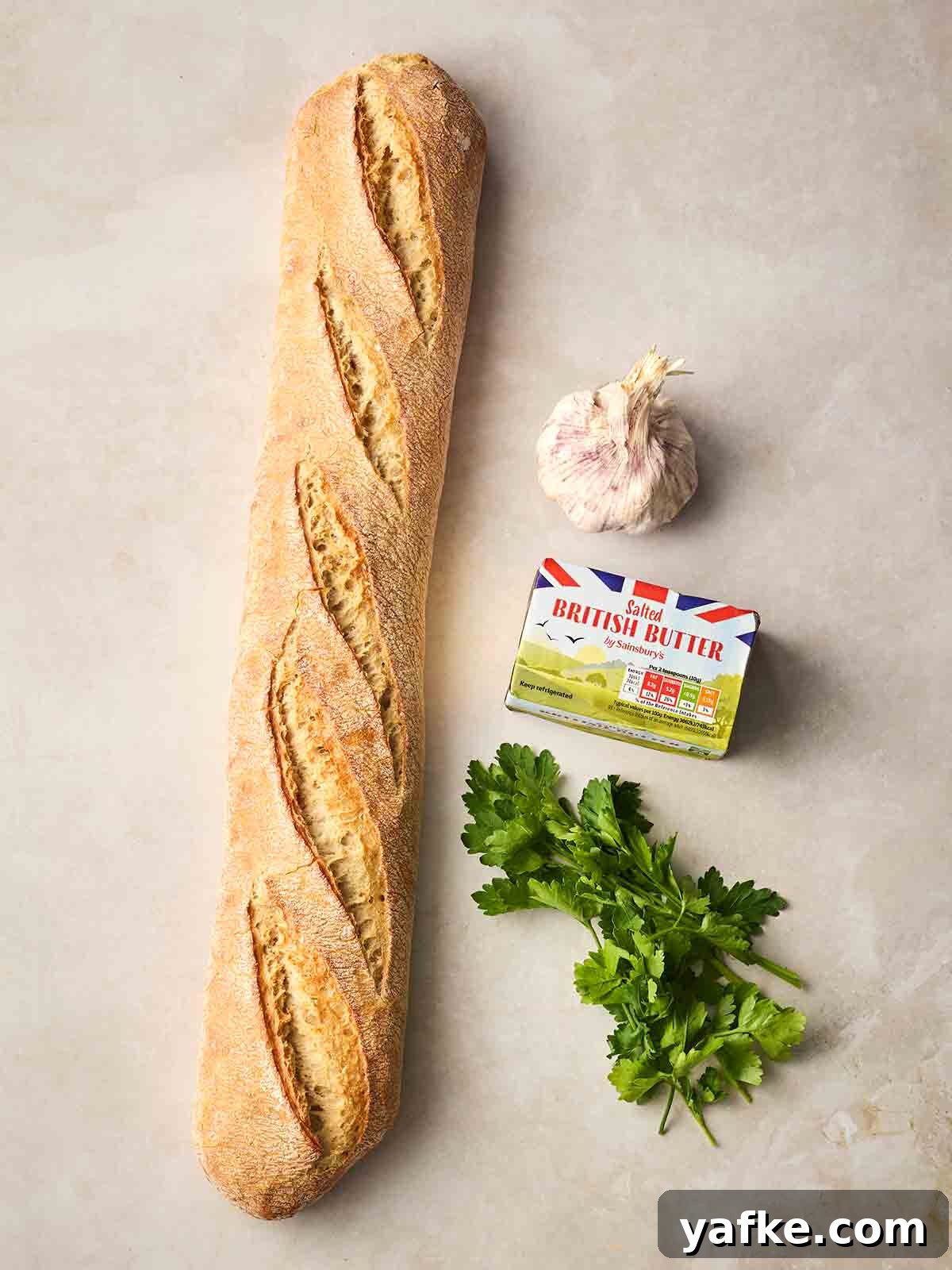 Crispy Garlic Bread Recipe with Herb Butter 4 The ingredients for making Homemade Garlic Bread laid out on a white counter.