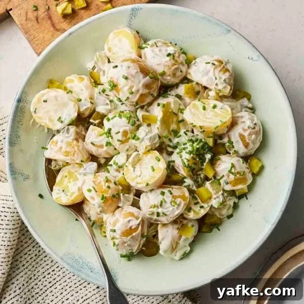 Crispy Garlic Bread Recipe with Herb Butter 5 A classic potato salad in a bowl, with sprinkled chives over the top, and a spoon in.