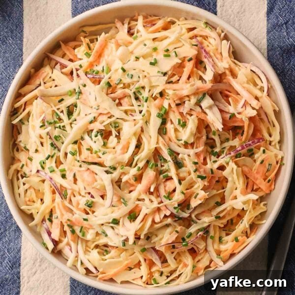 Crispy Garlic Bread Recipe with Herb Butter 6 A close up of a bowl with homemade coleslaw inside, with cabbage, carrots and chives on top.