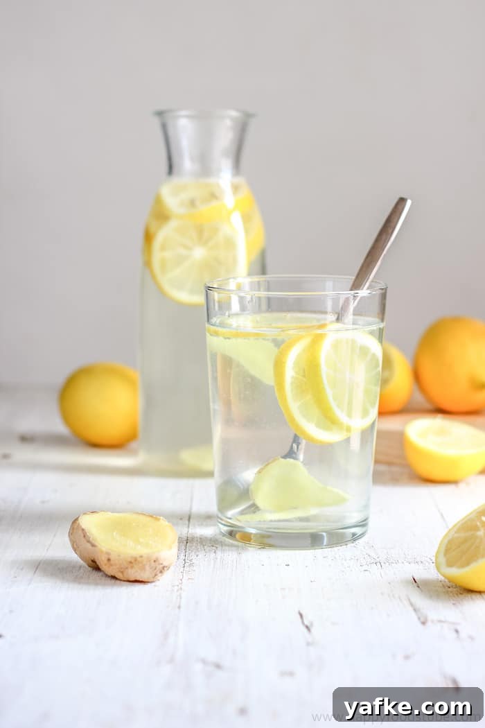 How to Make Lemon Ginger Water: Recipe and Benefits 2 Refreshing homemade drink with lemon and ginger served in a glass, with whole lemons in the background.