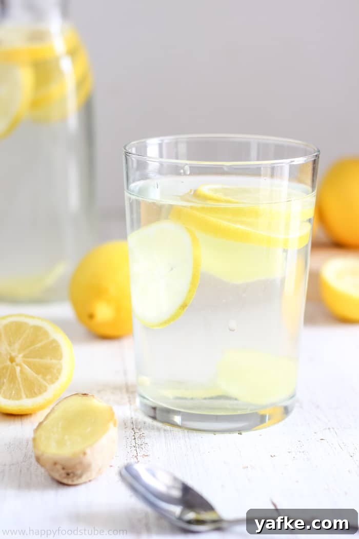 How to Make Lemon Ginger Water: Recipe and Benefits 5 Glass filled with sliced lemon and ginger in water, surrounded by fresh ingredients.