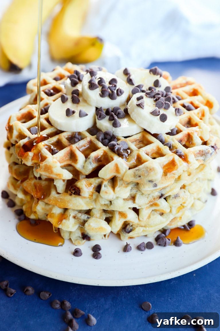 Drizzling syrup on a stack of breakfast pancakes with fresh fruit and chocolate