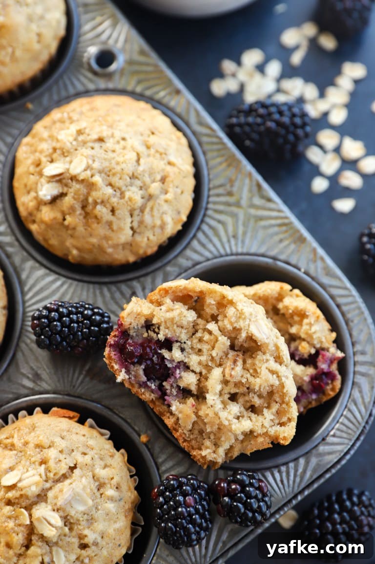 Half of a muffin in a muffin tin with fresh berries and oats