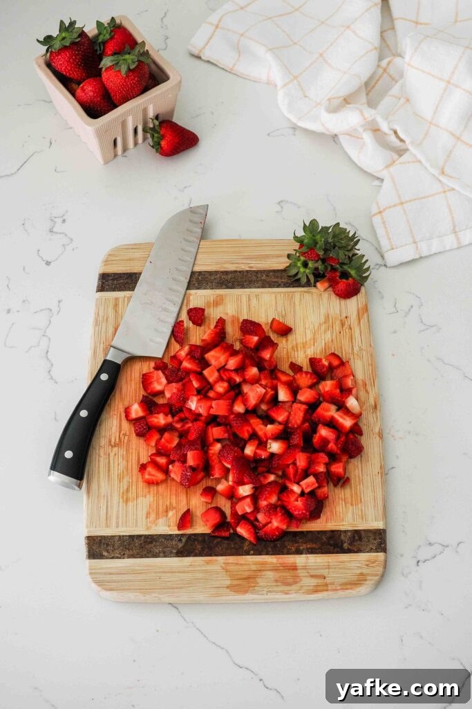 Creamy Homemade Strawberry Ice Cream Recipe 5 Diced strawberries on a wooden cutting board.