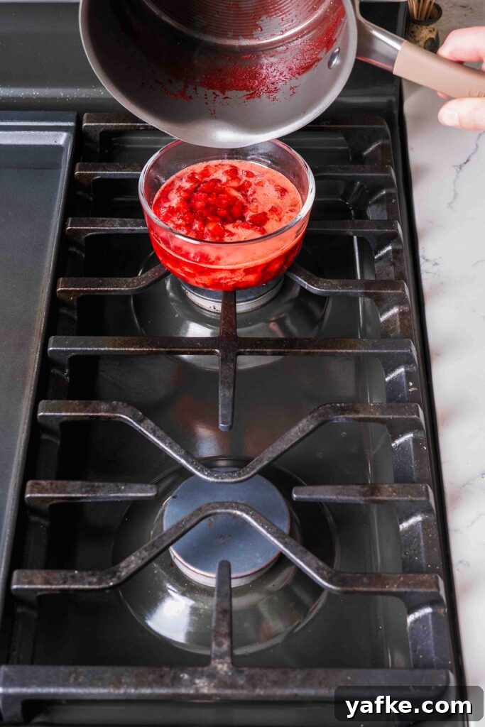 Creamy Homemade Strawberry Ice Cream Recipe 7 Strawberry jam is transferred from a pot to a glass container.