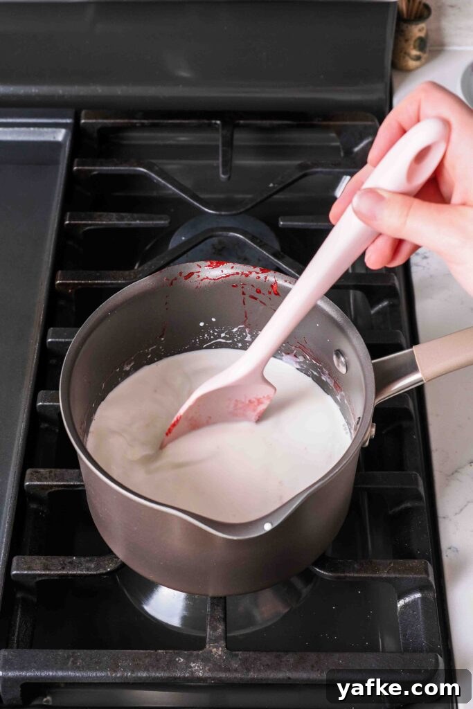 Creamy Homemade Strawberry Ice Cream Recipe 8 A spatula stirs milk and cream in a medium pot over medium heat.