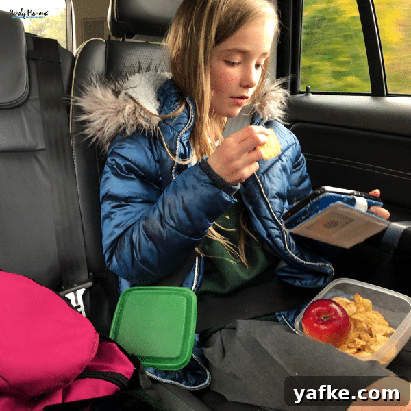 Smart Labeling Tips for Traveling with Kids 3 A child sitting in the backseat of a car, eating snacks from labeled containers, illustrating organized travel with kids.