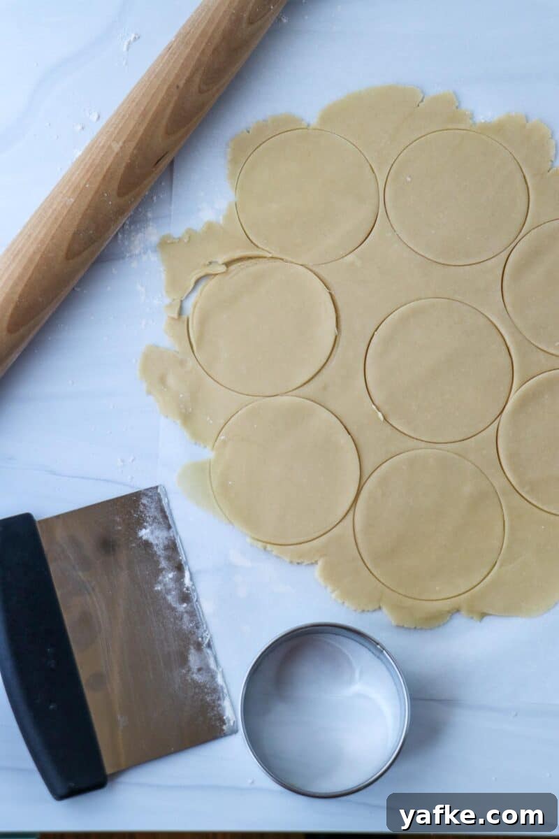 Vaniljhjärtan: Buttery Swedish Custard Heart Cookies 11 Rolled dough with circles cut out in it next to a rolling pin, pastry scraper and cookie cutter.