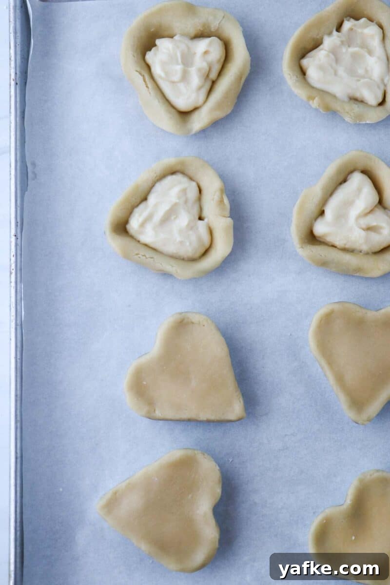 Vaniljhjärtan: Buttery Swedish Custard Heart Cookies 13 Pastry hearts on a baking sheet filled with pastry cream.