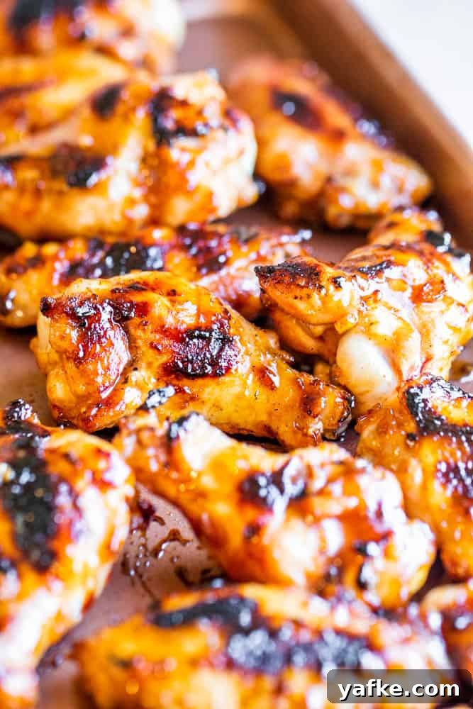 Cooked BBQ wings on a copper cookie sheet on a white table.
