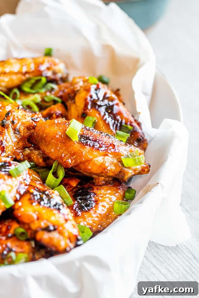 Grilled chicken wings in a white bowl on a white table.