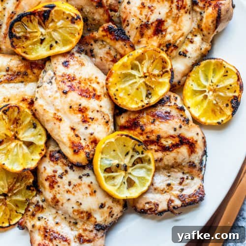 Overhead shot of chicken thighs on a white serving dish on a white counter.