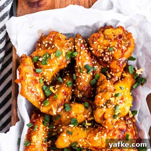 Overhead shot of wings in brown wooden bowl with parchment paper.