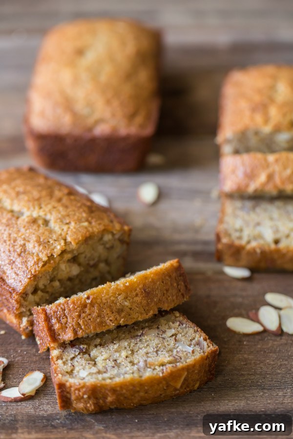 Moist Low-Sugar Banana Bread Recipe 2 Healthier Banana Bread mini loaf that has been sliced, with a whole mini loaf and another sliced mini loaf in the background.