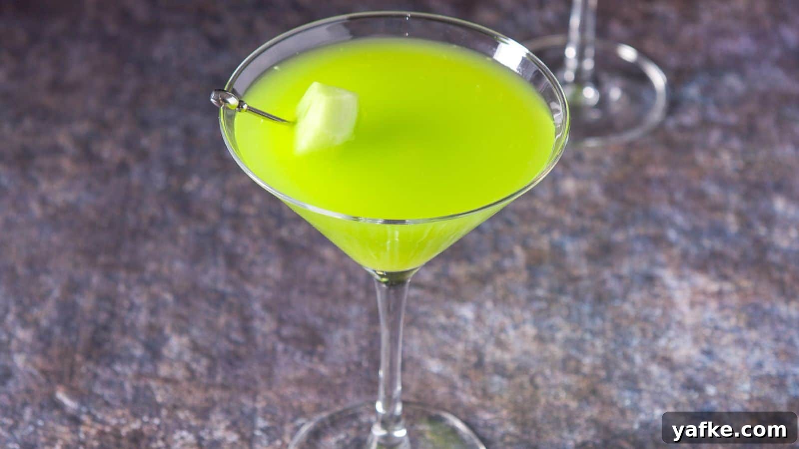 Melon Ball Cocktail Recipe: How to Make the Classic Drink 3 A martini glass filled with the green cocktail with some melon on a pick