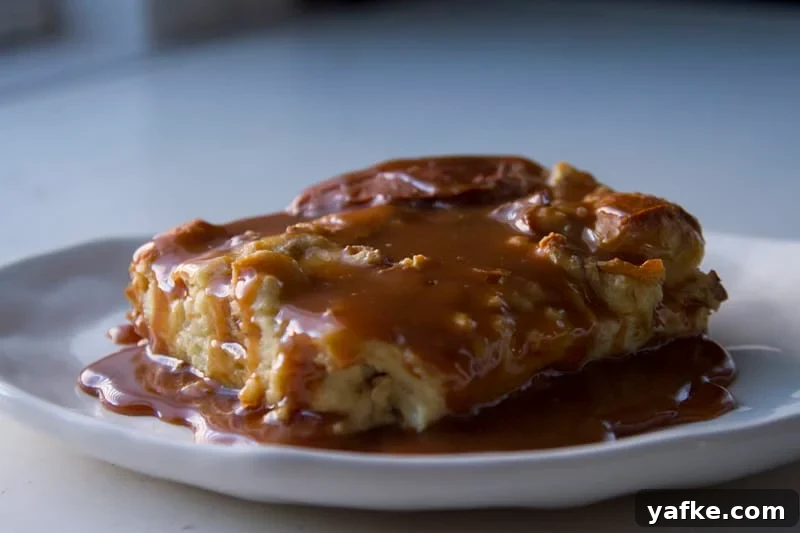 Salted Caramel Pretzel Banana Bread Pudding Recipe 2 A serving of pretzel banana bread pudding on a white plate covered in salted caramel sauce.
