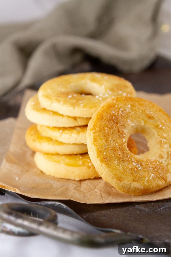 Classic Danish Salted Butter Cookies Recipe 9 A stack of butter cookies on a metal tray with a green napkin in the background.