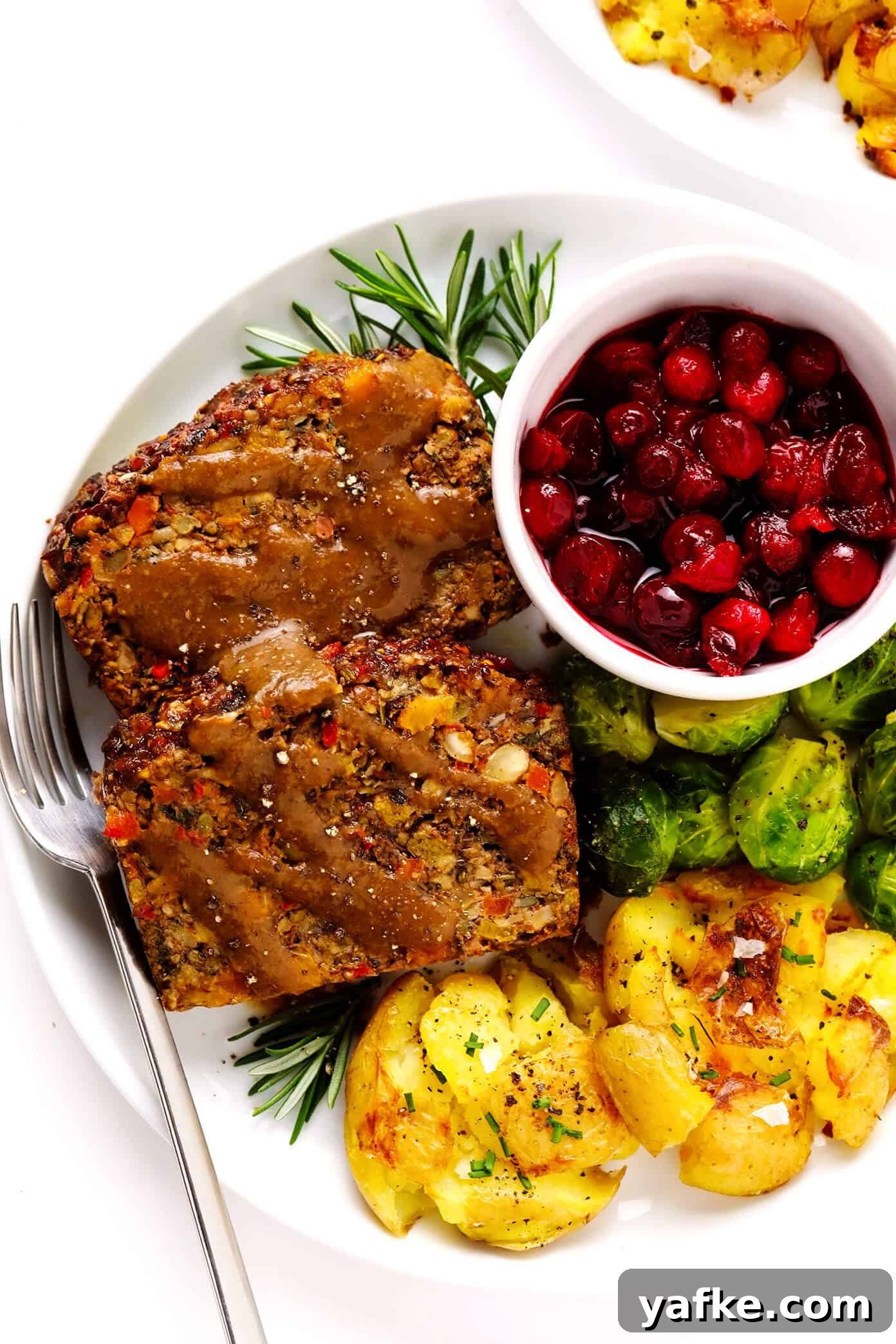 Nut roast plated with sides Nut Roast with Gravy, Smashed Potatoes, Roasted Brussels Sprouts and Cranberry Sauce