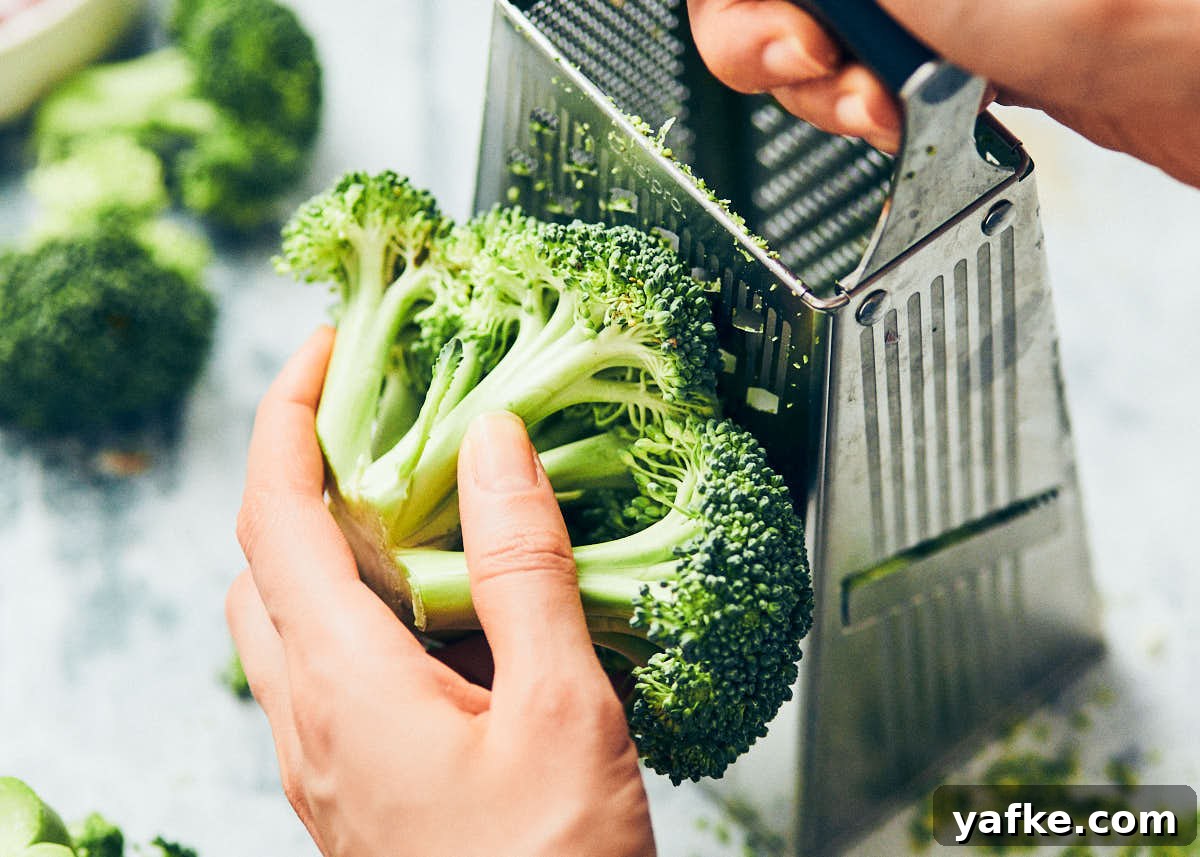 Crispy Air Fryer Broccoli Tater Tots 5 Grating broccoli on a box grater for broccoli tater tots.