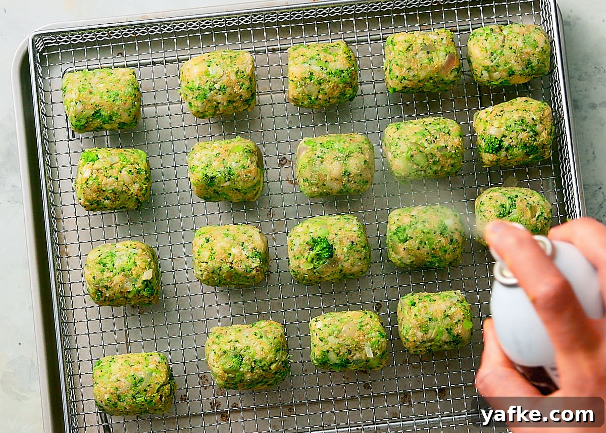 Crispy Air Fryer Broccoli Tater Tots 9 Spraying broccoli tots with oil spray before baking in air fryer.