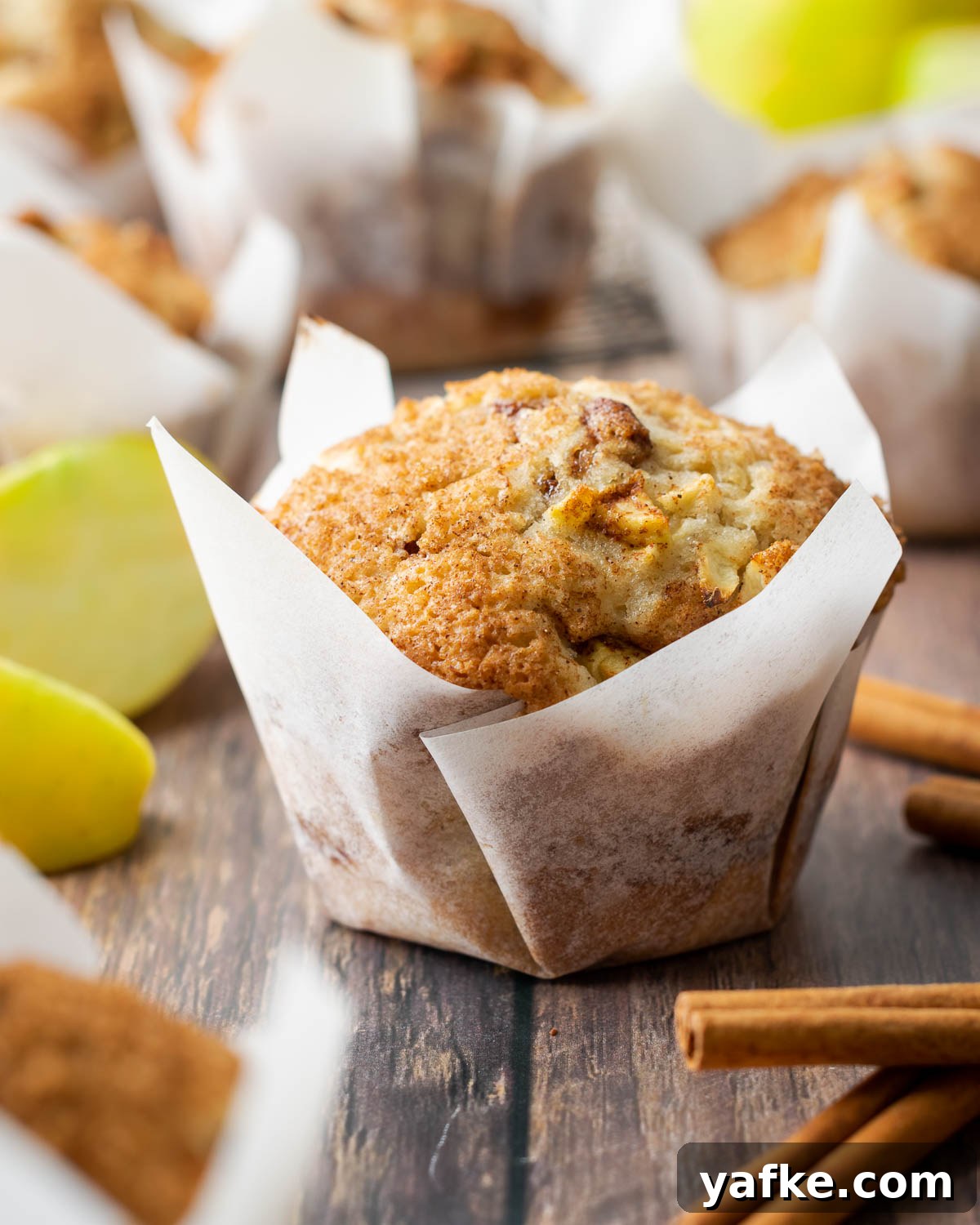 Gluten-Free Apple Cinnamon Muffins 2 A gluten free apple muffin sprinkled with sugar and cinnamon sitting on a wooden table.