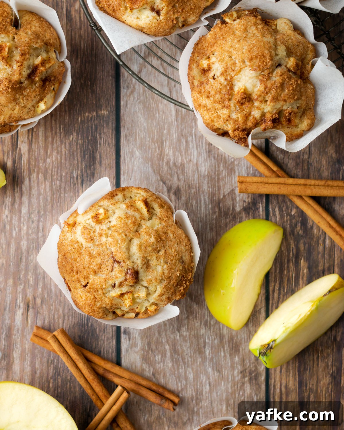Gluten-Free Apple Cinnamon Muffins 12 Four gluten free apple muffins sitting on a cooling rack on a wood table.