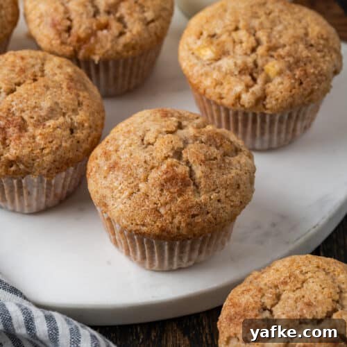 Gluten-Free Apple Cinnamon Muffins 15 A batch of apple banana muffins sitting on a white marble cutting board.