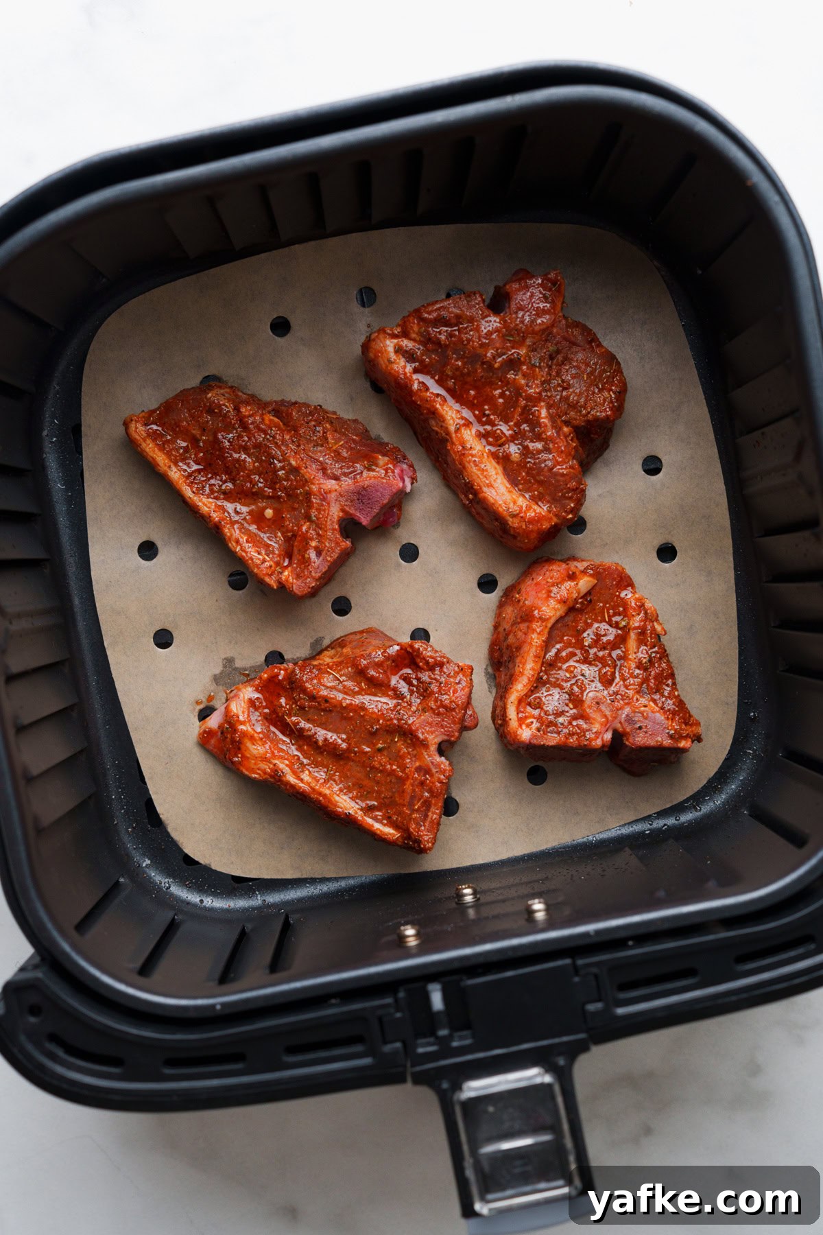 Air Fryer Lamb Chops Recipe with Garlic and Herbs 6 Four marinated lamb chops in air fryer.