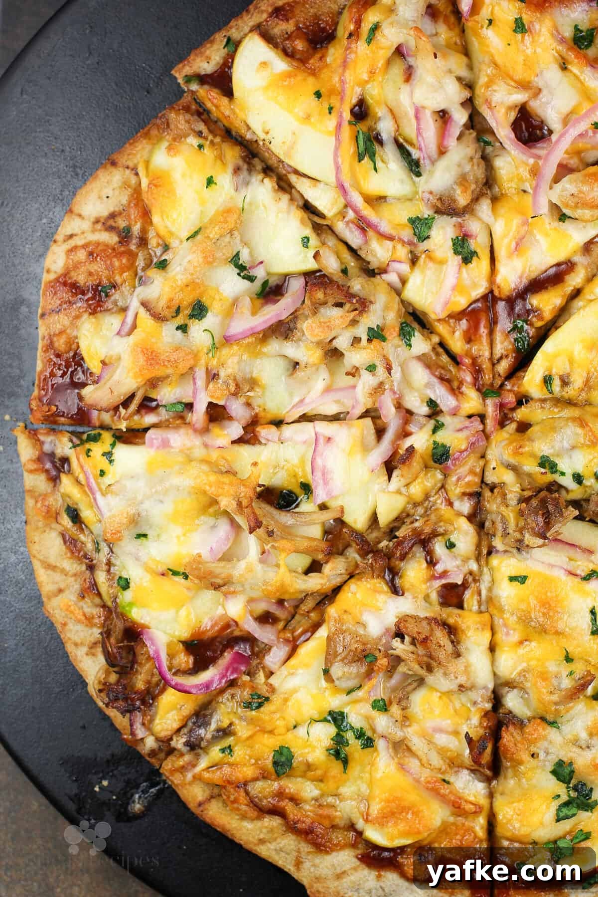 Caramelized Apple and Pulled Pork Pizza 4 sliced pizza on black pizza stone.