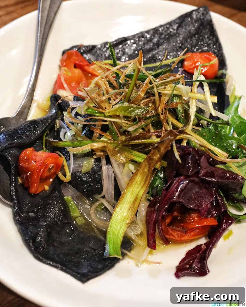 Bold Banff Adventures: What to Do in Banff National Park 12 mushroom ravioli with tomatoes and leeks on a white plate with spoon.