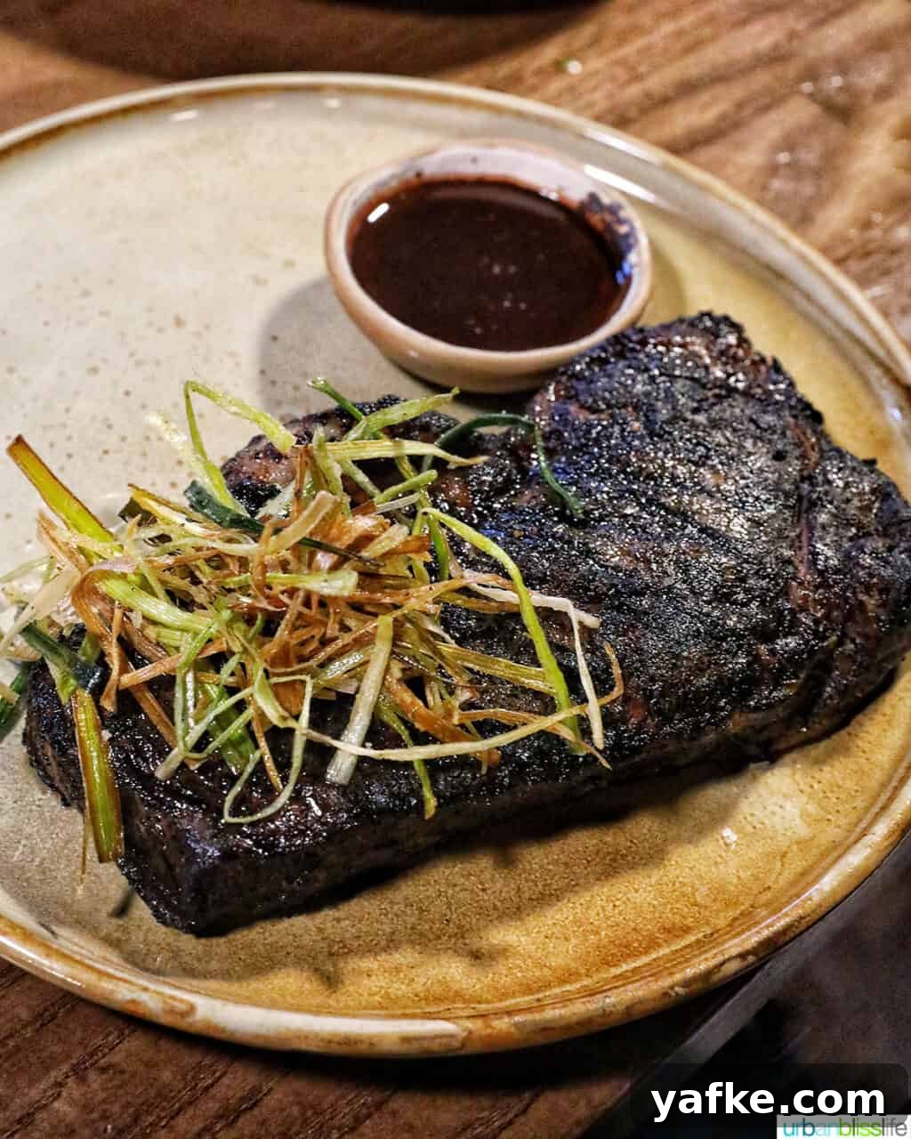 Bold Banff Adventures: What to Do in Banff National Park 13 coffee rubbed steak topped with crispy leeks and side of jus on a plate.