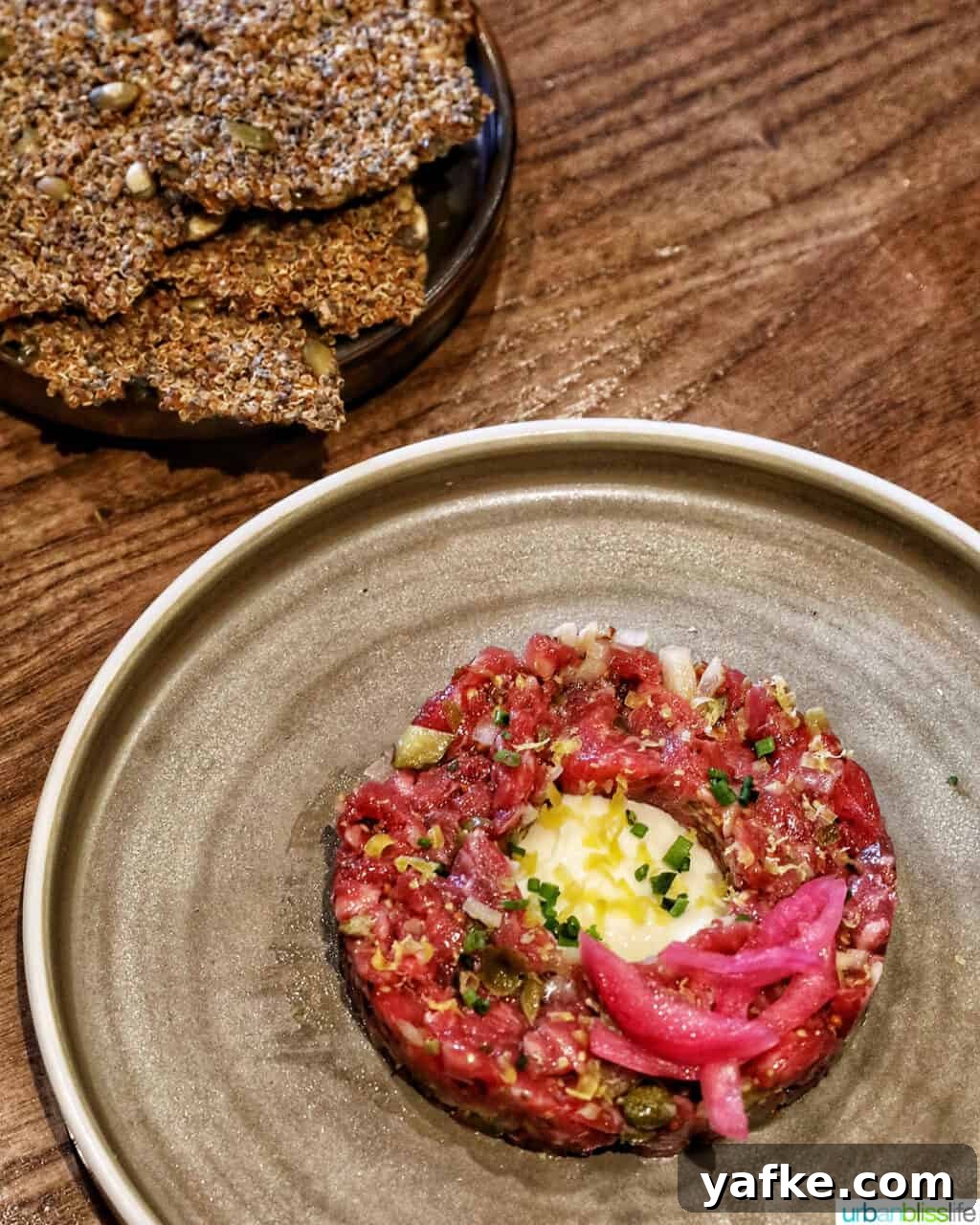 Bold Banff Adventures: What to Do in Banff National Park 7 bison tartare on a cream colored plate with side of crackers.