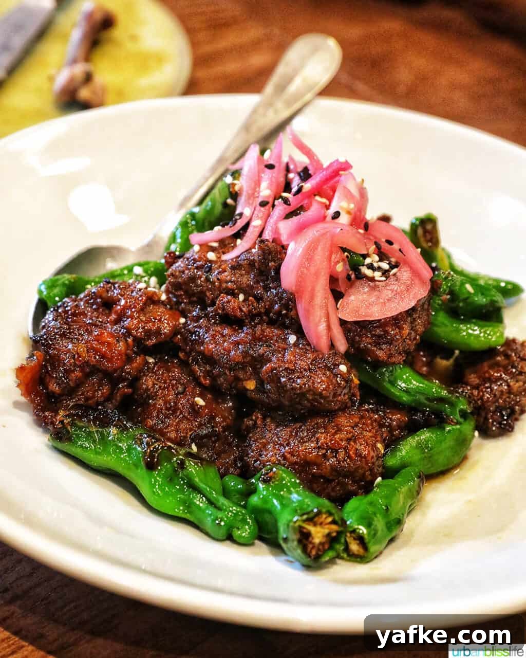 Bold Banff Adventures: What to Do in Banff National Park 10 ginger beef with pickled onions and peppers on a white plate.