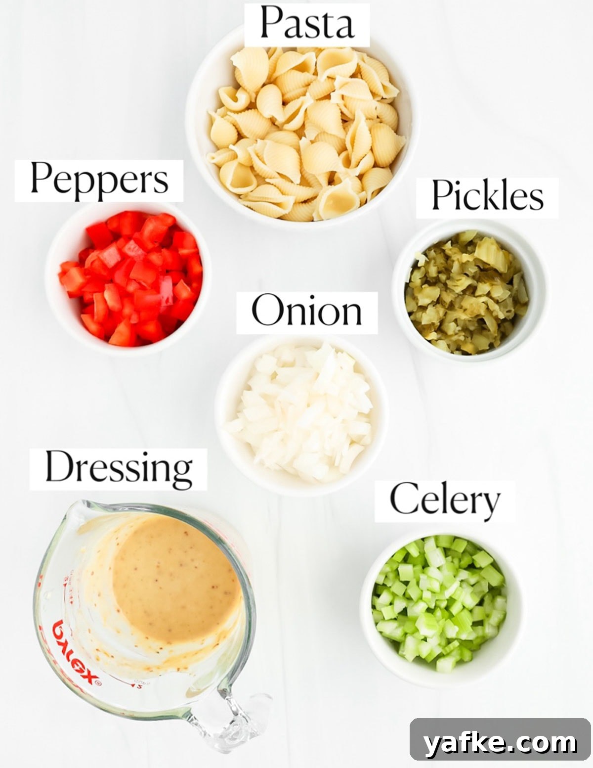 Creamy Vegan Macaroni Salad Recipe 3 Labeled ingredients in white bowls including pasta, red peppers, pickles, onion, dressing, and celery