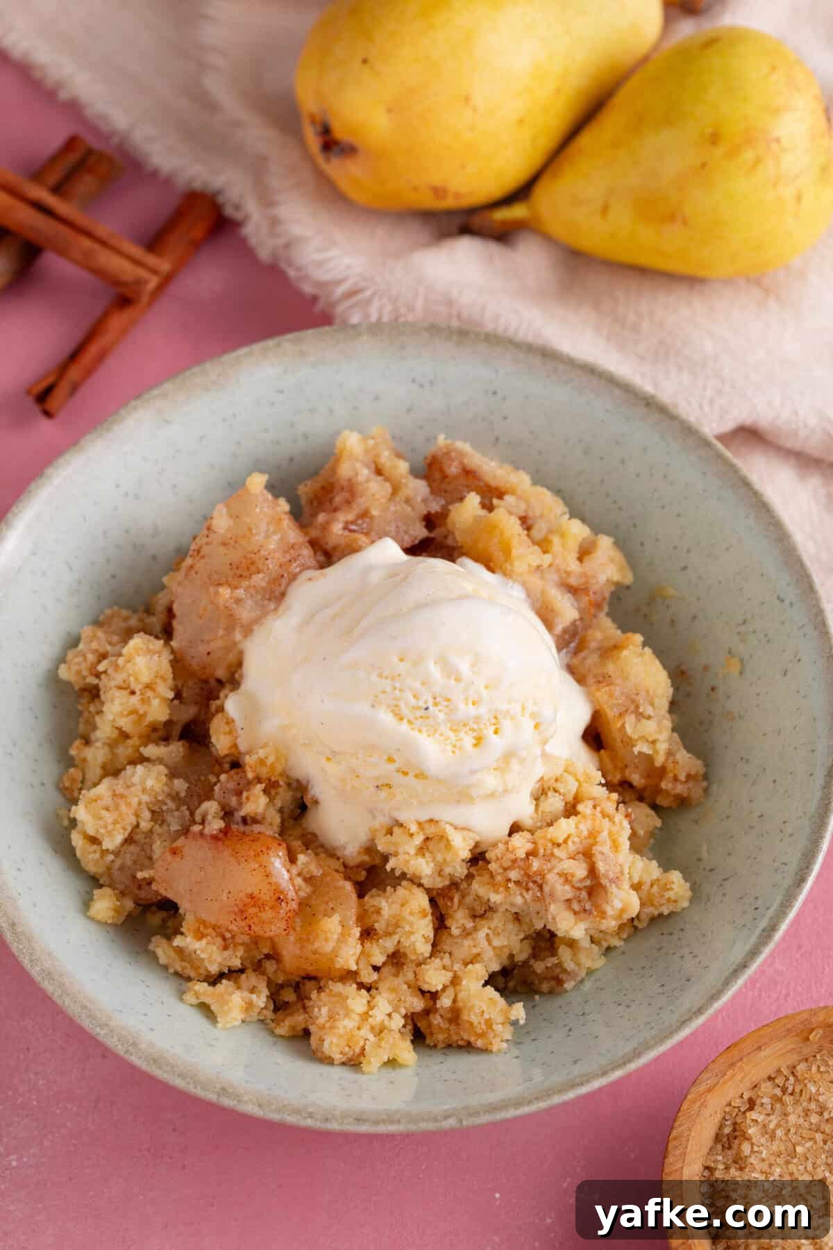 Gluten-Free Pear Crumble Recipe with Cinnamon Streusel 3 A bowl of spiced pear crumble with a scoop of ice-cream on top.