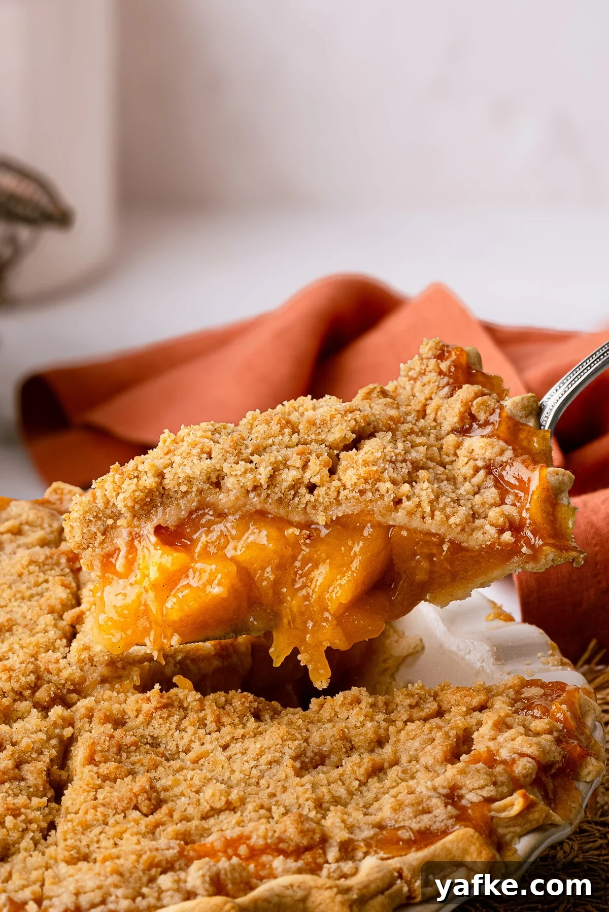 Classic Peach Crumble Pie with Brown Sugar Streusel 14 Slicing a deep dish peach pie, showing off a clear, velvety filling and a golden brown crumb topping.