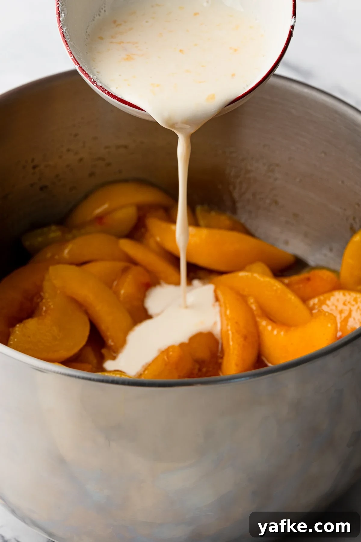 Classic Peach Crumble Pie with Brown Sugar Streusel 6 A white cornstarch slurry being poured into a bubbling pot of stovetop peach pie filling to thicken the juices.