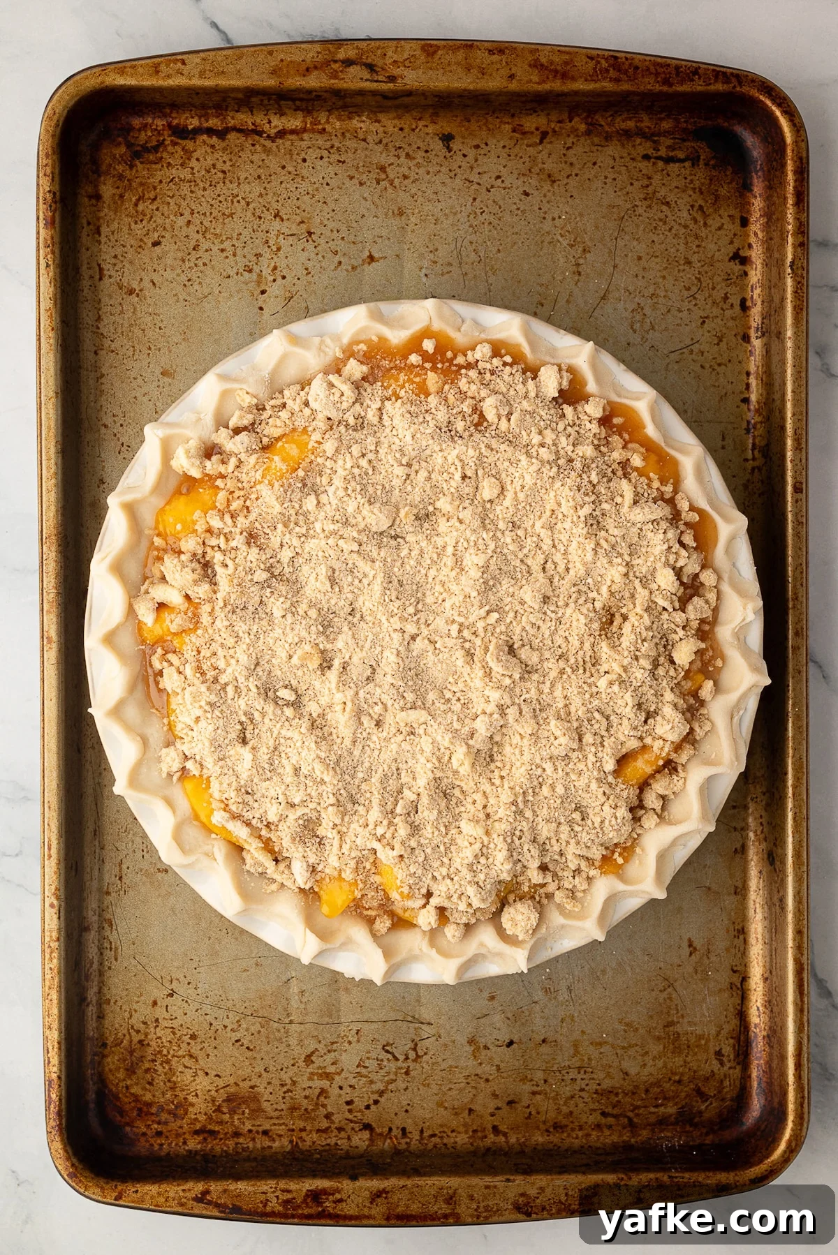 Classic Peach Crumble Pie with Brown Sugar Streusel 9 Deep-dish peach pie generously covered with a thick layer of butter crumb topping before baking.