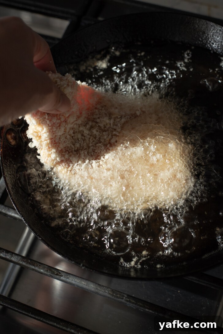 How to Make Crispy Japanese Tonkatsu in 30 Minutes 10 Breaded pork cutlets being lowered into hot oil in a skillet