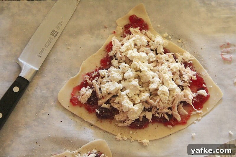 Turn Leftover Turkey into Cranberry and Boursin Hand Pies 3 Overhead shot of Boursin cheese on top of turkey on top of cranberry sauce on pie dough.