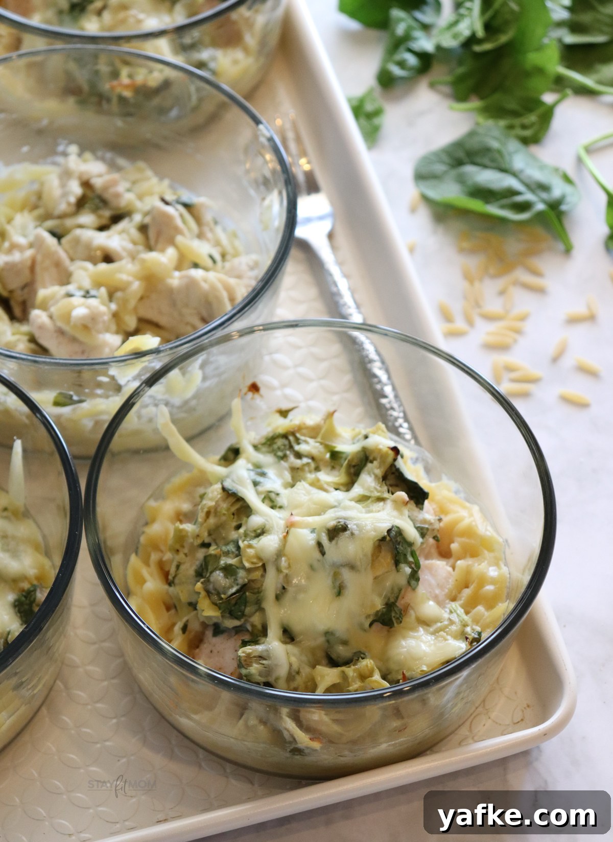Creamy Spinach and Artichoke Chicken Orzo Bake Recipe 3 Spinach Artichoke Chicken Orzo Bakes plated with melted cheese on top.