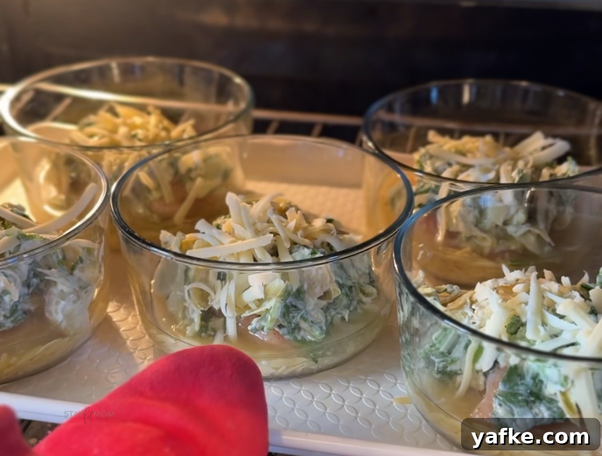 Creamy Spinach and Artichoke Chicken Orzo Bake Recipe 5 Close up of a ramekin-style bowl filled with orzo, chicken, spinach, artichoke, and melted cheese.