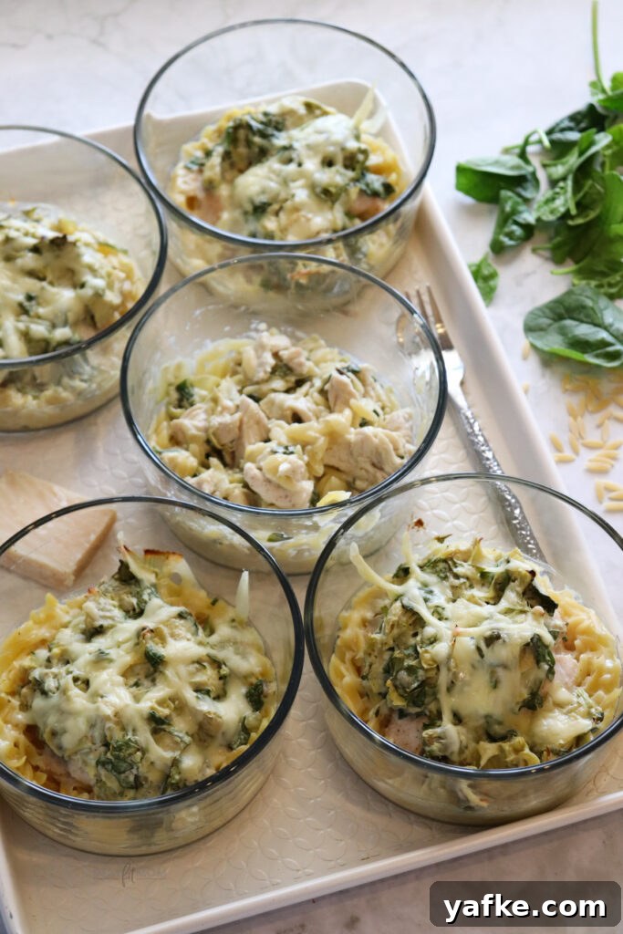 Creamy Spinach and Artichoke Chicken Orzo Bake Recipe 6 Multiple prepared Spinach Artichoke Chicken Orzo Bakes in glass meal prep containers ready for the oven.